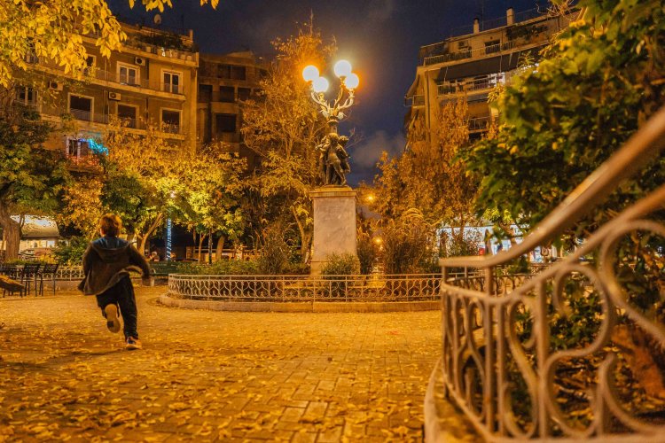 a young boy running around the square, night time, yellow lighting. 