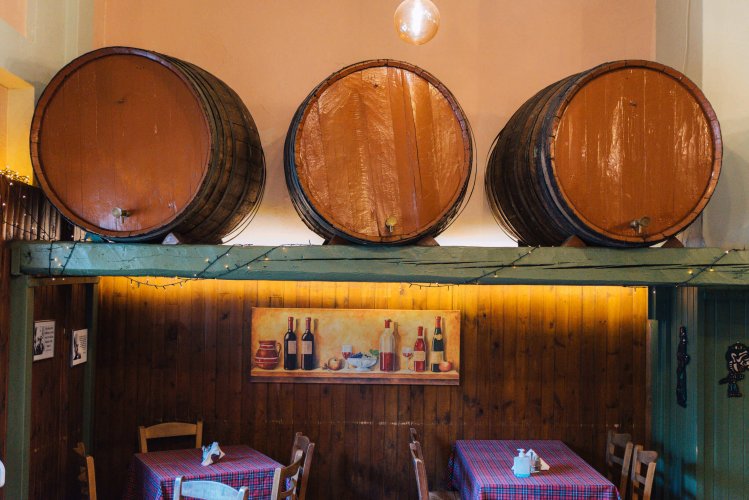 three wooden wine barrels above two set tables at a grill house. 