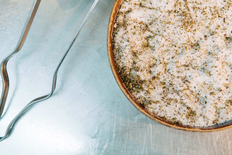 a bowl with a mix of salt, pepper, oregano, and a tong. 