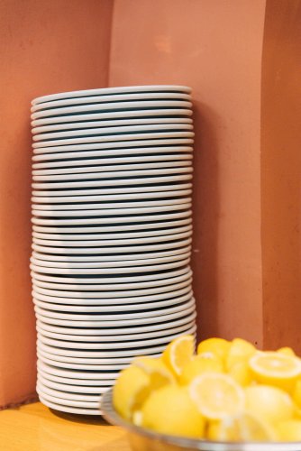 a pile of white dishes and a plate with lemons.