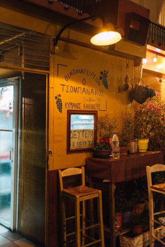 the entrance of a grill house, a table and chairs, a yellow light, letters on the wall.