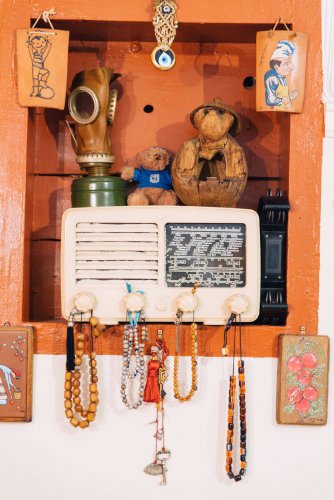 a shelf with vintage objects, photos, radio, worry beads. 