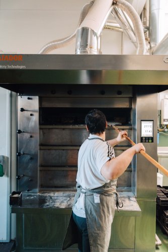 a pastry chef putting bread in the oven.