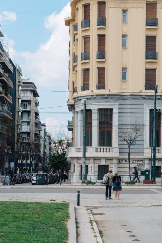 a building with circular facade, other blocks of flats, people walking. 