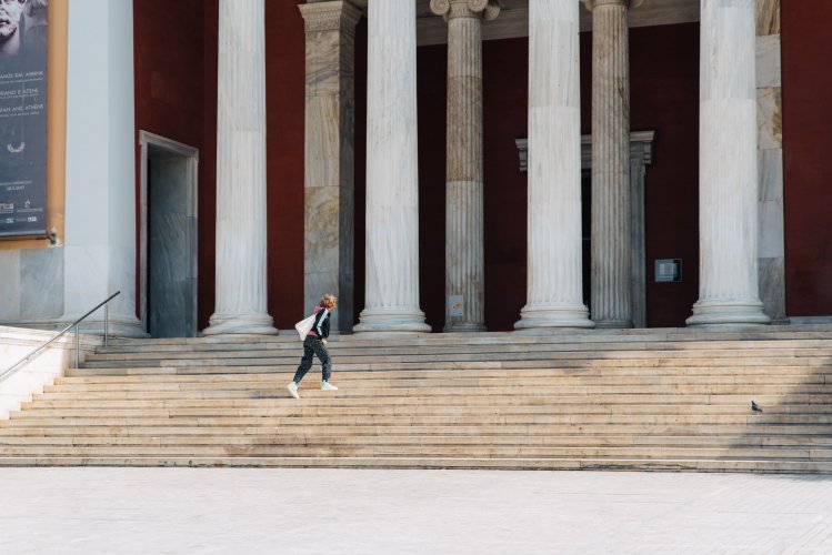 a woman climbing up the stairs to enter a musum.