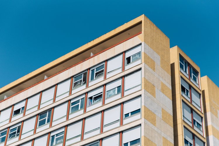 the peak of a block of flats, blue sky above. 