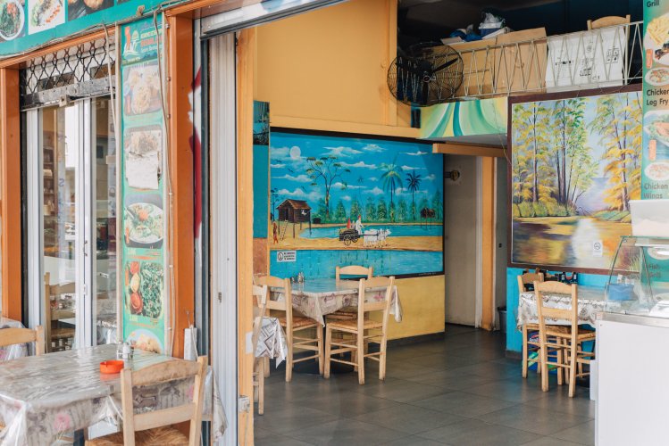 the interior of a resturant, set tables, a mural with a seashore.