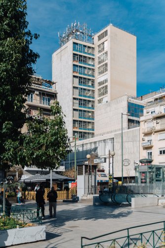 a square, coffee shops, people, a metro station and buildings around. 