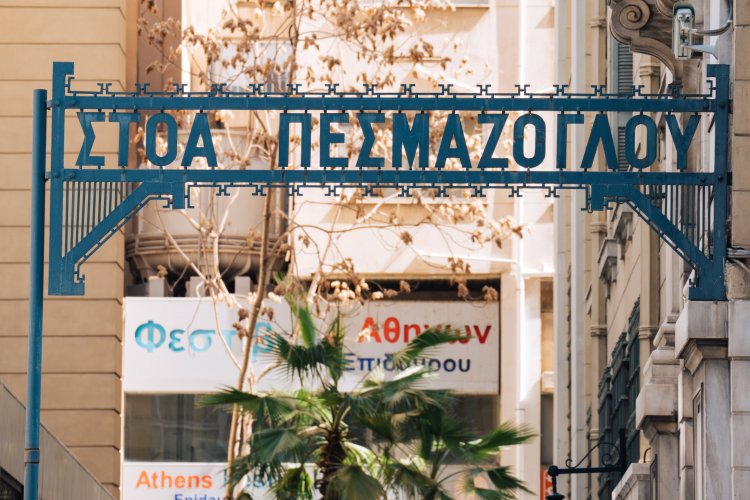 the blue entrance sign of an arcade that reads "Pesmazoglou arcade", other signs in the background.