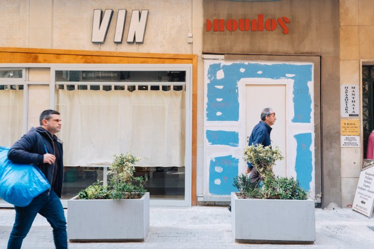 people passing by shop, a sign that reads "VIN" and a cut-in-half sign of an old door handles and doorknob shop.