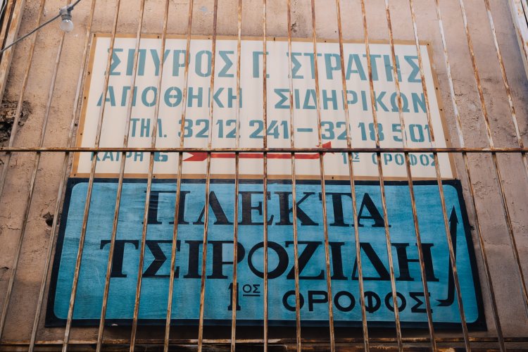 two old signs of closed stores on a wall behind rails. 