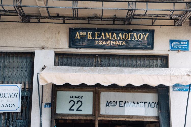 signs that reads "Elmaloglou textile" and "Aiolou 22", at the shop's entrance.