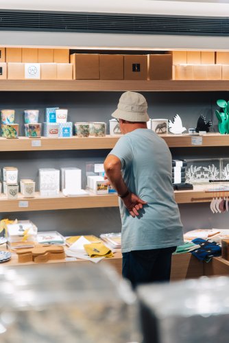 a man looking at items on dispaly at a museum shop.