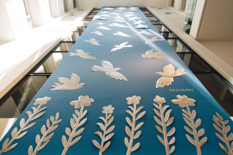A large-scale installation with flowers and birds on blue background.