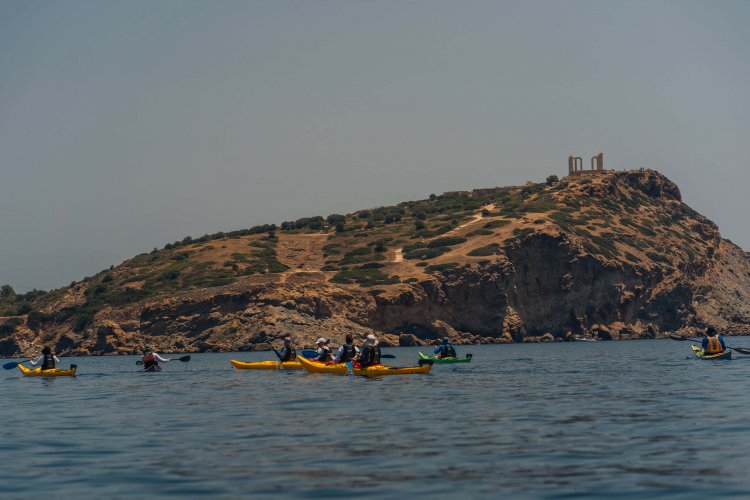 people kayaking beneath an ancient temple.