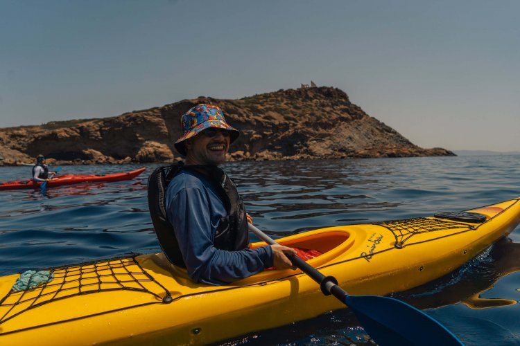 a man smiling in a yellow kayak at sea