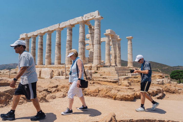 three people walking pass an ancient temple.