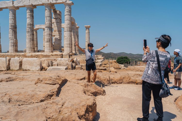 a woman posing in front of an ancient temple, a man taking a photo of her.