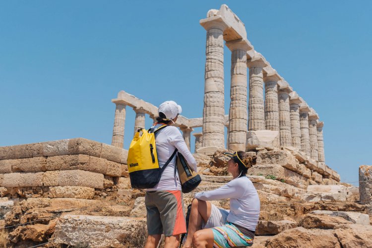 two women, one sitting down, looking at an ancient temple.