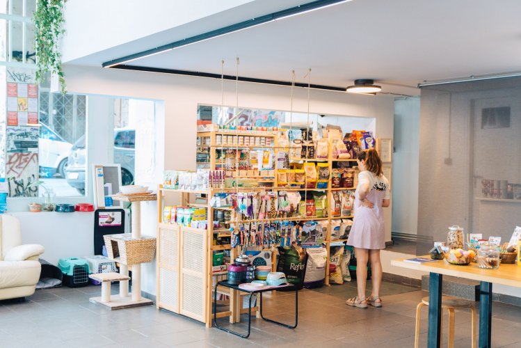 the inside of a pet store, a woman standing in front of shelves with pet food and snacks