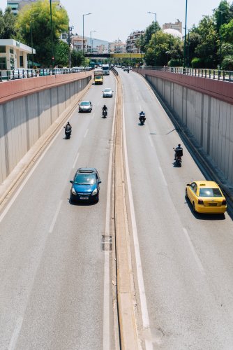 cars moving under a bridge towards an avenue. 