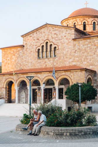 two older men sitting outside of a church.