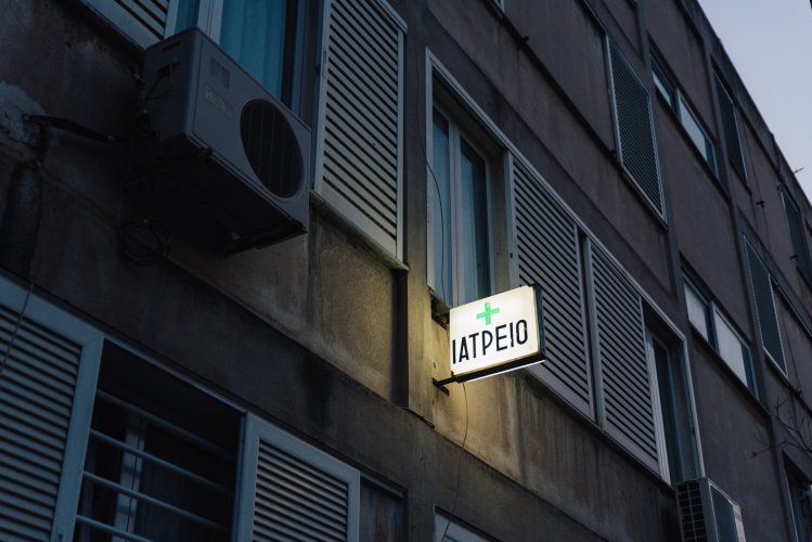 a bulding with a lighted sign that reads "doctor's office" in greek.