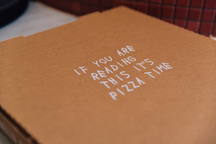 a pizza takeaway box with lettering that reads "if you are reading this it's pizza time"