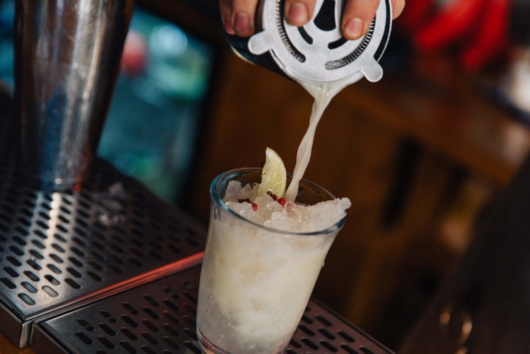 a white-coloured cocktail being served in a glass