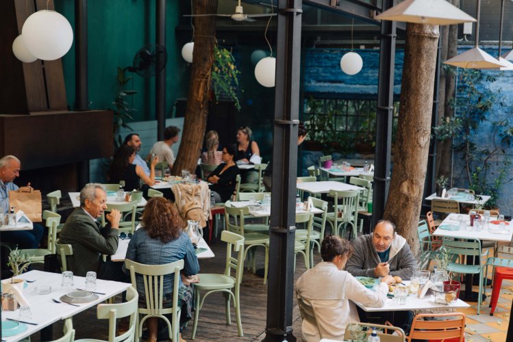 people eating at a restaurant, olive green wooden chairs, white tables