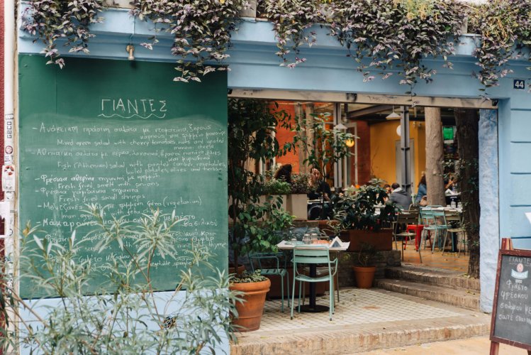 the outside of a restaurant, menu written on a greenboard with chalk next to the entrance