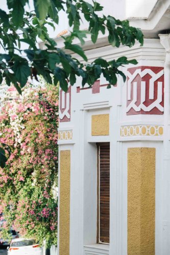 side of a building with yellow and red details, trees around.