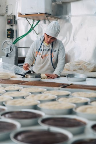 a woman buttering a dessert with a basting brush