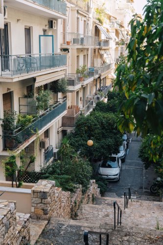 pedestrian stairs going down, blocks of flats, trees and parked cars.