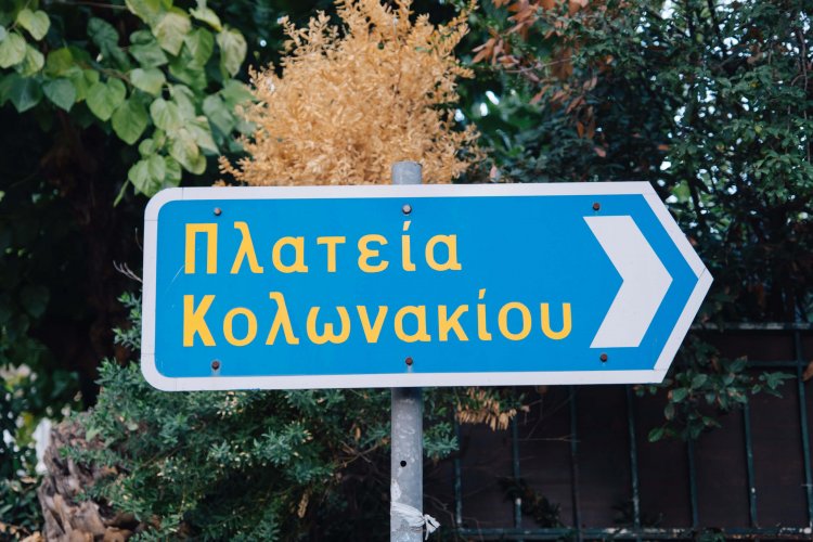 a road sign that reads "kolonaki square", trees around