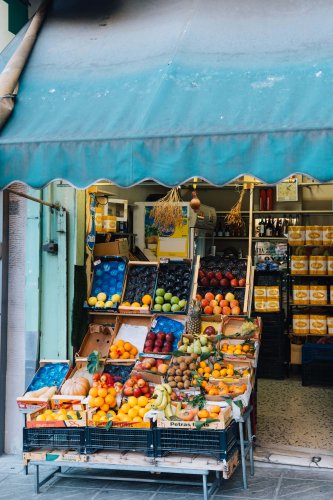 a fruit shop with a blue tent, fruits on display