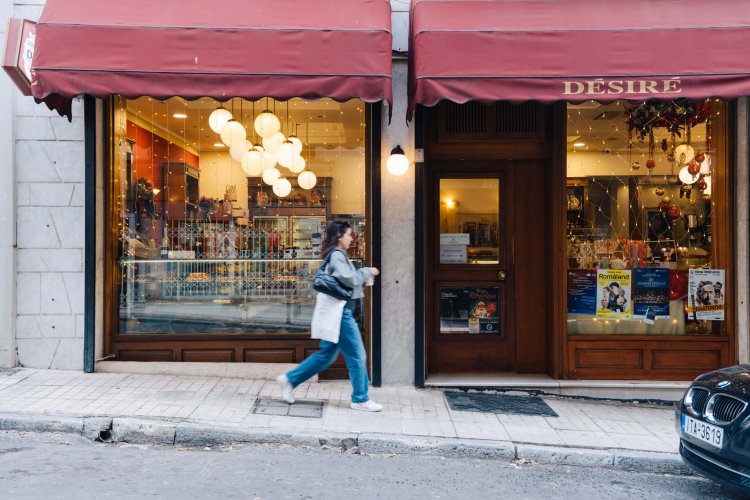 a woman passing outside a pastry shop with red tent that writes "Désiré".