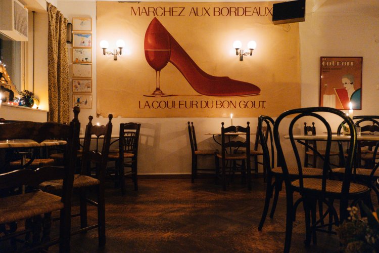 the interior of a bar with tables and chairs and a poster that reads "marchez aux bordeaux, la couleur du bon gout"