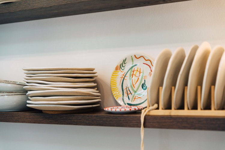 A stack of dinner plates on a wooden shelf.