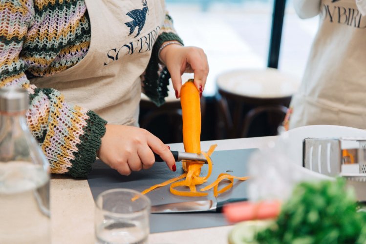 A person peeling a carrot with a peeler