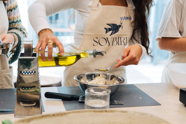 A woman pouring olive oil from a glass bottle into a bowl.