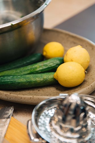 A plate with cucumbers and lemons next to a bowl.