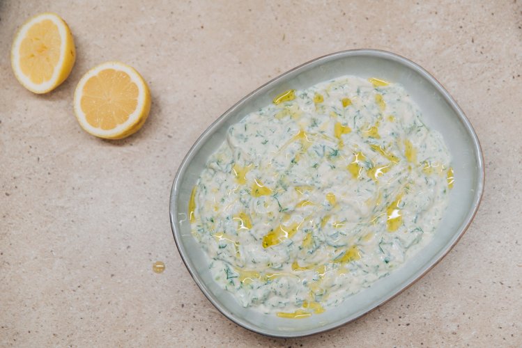 a bowl with tzatziki, a lemon cut in half next to it. 