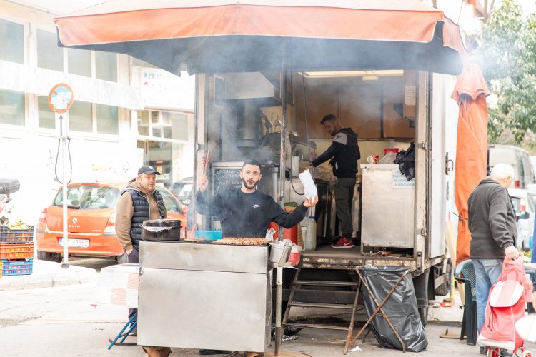 men grilling souvlaki at a farmers' market.