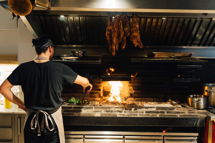 a chef adding broccoli on the grill.