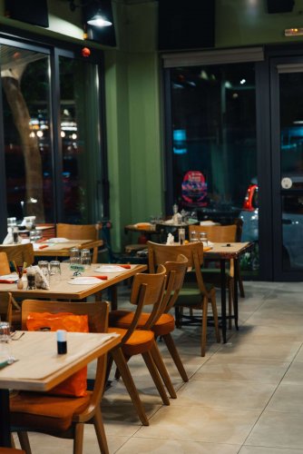 A row of set tables and chairs in a dimly lit restaurant.