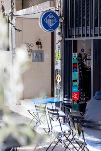 the entrance of a restaurant, a sign that reads "baba ghanoush", outside tables and chairs