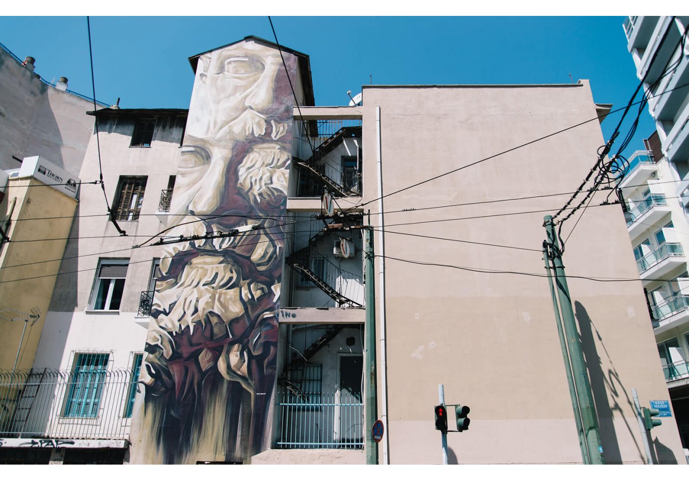 Face of Socrates graffiti on part of building seen through electrical power wires