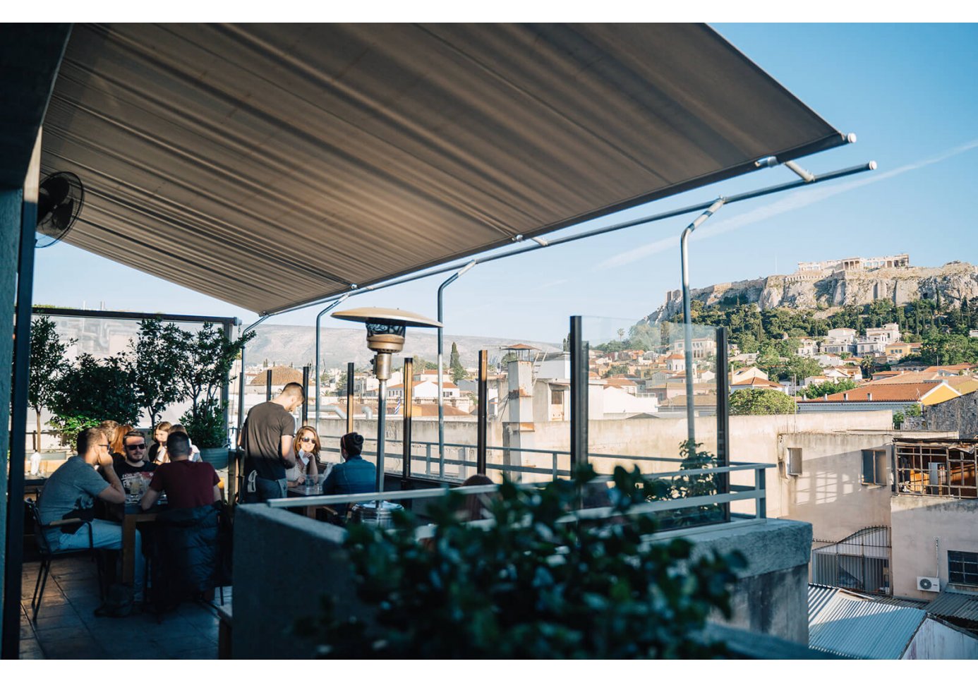 People sitting at Couleur Locale rooftop bar in Athens with Parthenon views. 