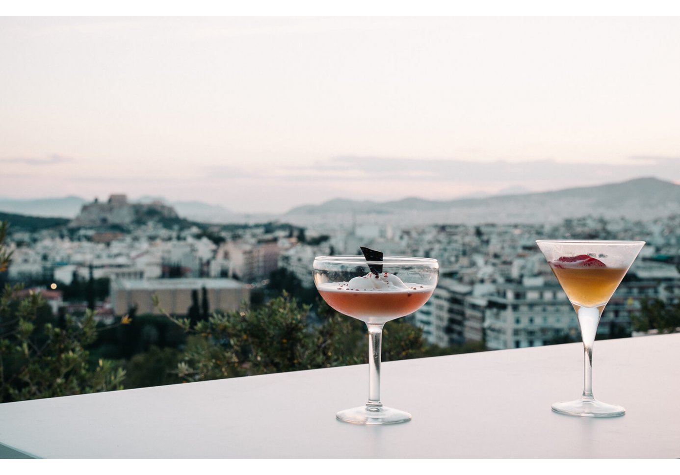 Two cocktail glasses and a view of Athens from Galaxy bar at the Hilton.